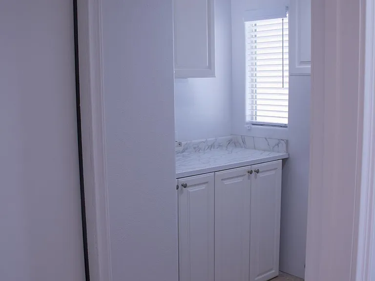 Laundry room with washer and dryer hookup as well as newly installed cabinets and granite counter top. Leads into the garage