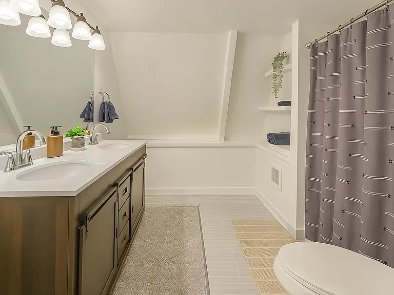 Spacious full bath with double vanity, built-in shelving, and modern lighting_perfect for getting ready with ease.