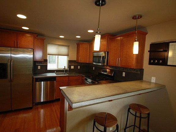 This dream kitchen features stainless appliances, custom cabinetry, and both stainless and concrete 