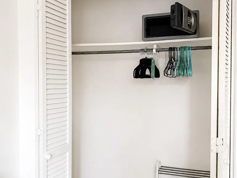 Closet storage with hanging rod, shelf space, and louvered doors for organizing clothing and personal items.