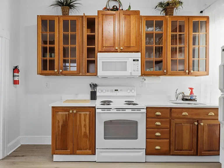 Kitchen with generous wood cabinetry, glass-front uppers, and a full appliance set plus stainless sink and prep area.