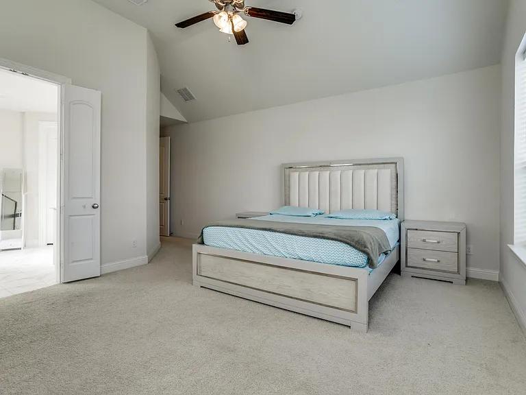 Carpeted bedroom with ceiling fan and lofted ceiling