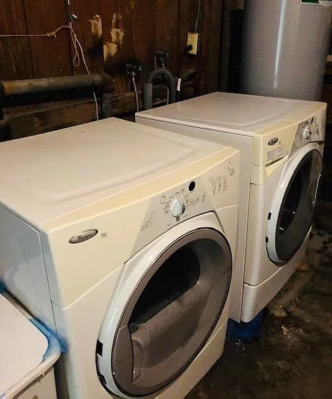 Shared washer and dryer in storage room.