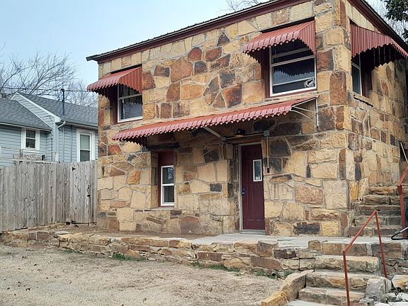 Front door to apartment with privacy fence in yard. Covered porch with Ring doorbell camera