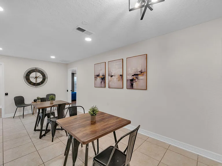 Dining area with two tables, tiled flooring, recessed lighting, and easy flow to adjacent rooms for shared meals.