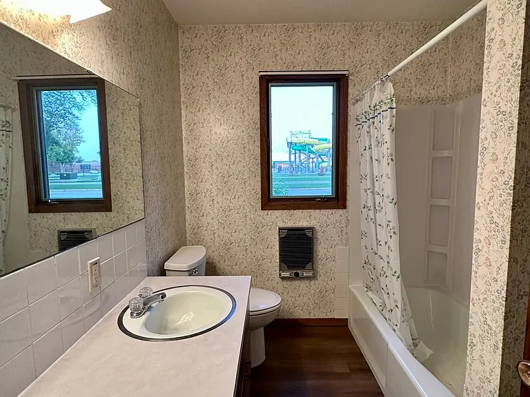 The bathroom is functional and well-maintained, featuring a full tub/shower combination, large vanity with ample counter space, and a window that provides natural light.
