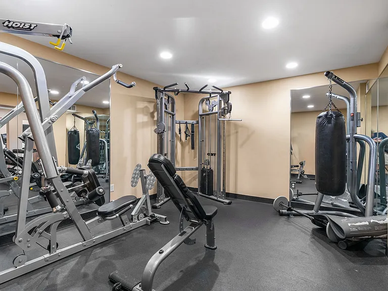 A gym with a variety of equipment including treadmills, weights, and exercise machines.
