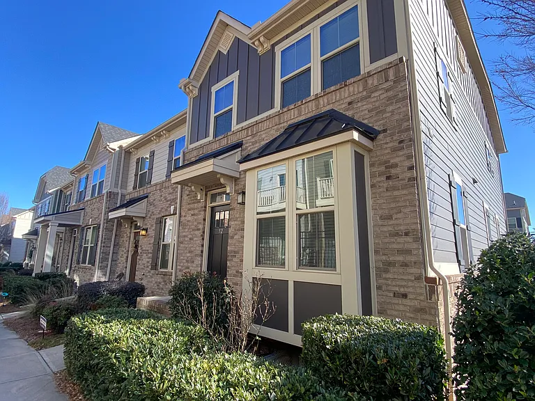 End unit with bay window, sidewalk leading to community green space beside unit and in the middle of the High View Townes neighborhood