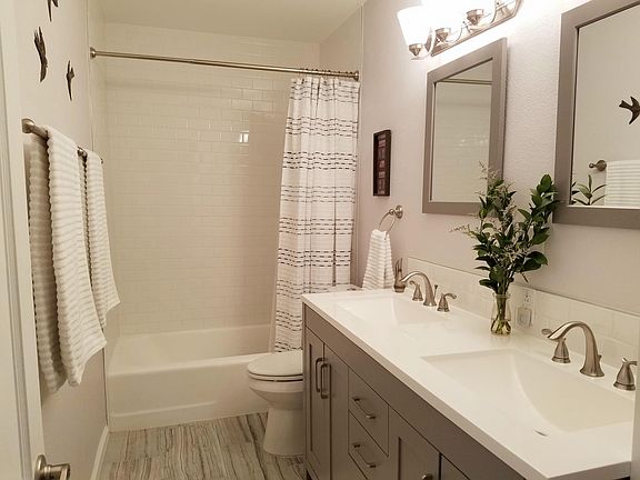 Fully remodeled main bathroom with double sinks and beautiful white subway tile tub surround
