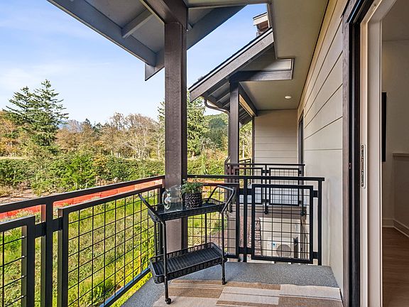 A cozy porch with a metal railing overlooks a lush, forested landscape in the background.