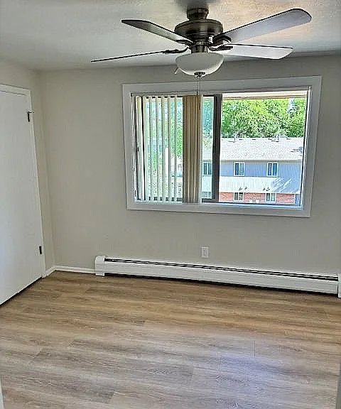 Bright and airy room with modern ceiling fan, large window offering a scenic view, and sleek hardwood flooring.