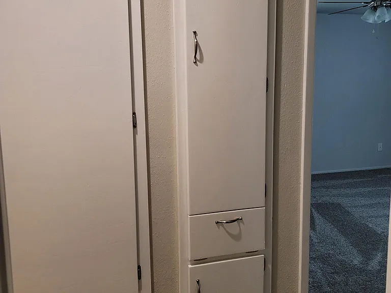 Additional storage in the hallway with clothes hamper located on the bottom.