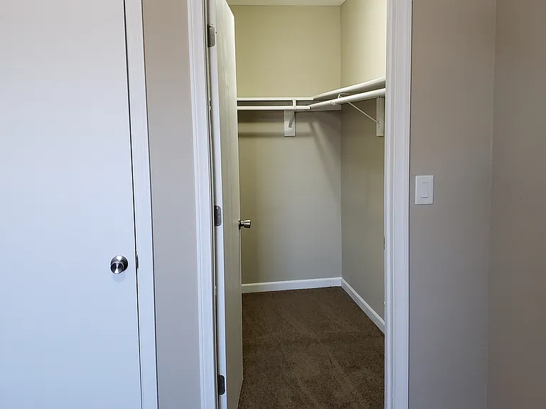 Walk in master closet with a small coat closet to the left