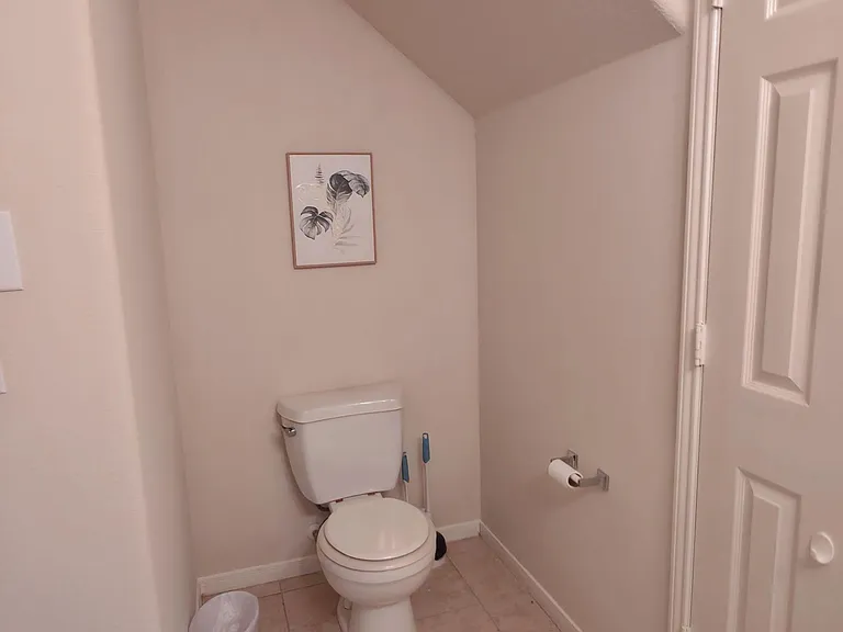 Half bath with tile flooring, neutral walls, and convenient under-stair layout for guests and everyday use.
