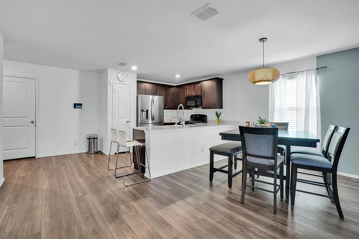 Open-concept kitchen and dining area featuring wood-finish flooring, dark wood cabinetry, stainless steel appliances, and a breakfast bar - 2919 Cascade Ln