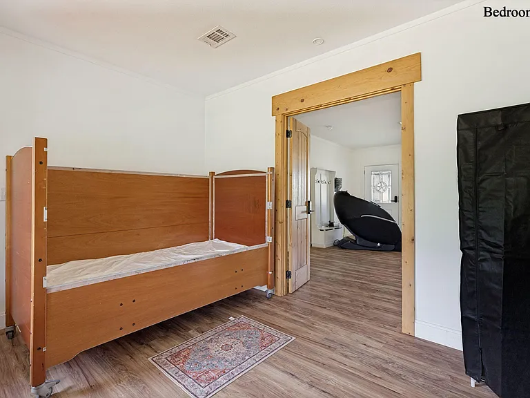 Private bedroom with durable flooring, a bed frame in place, and convenient access to the main living areas.