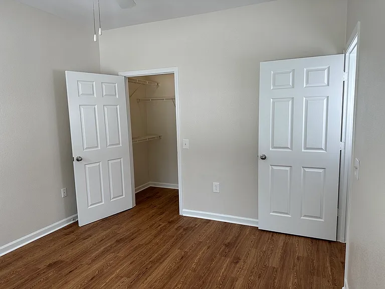 Bright and inviting room featuring elegant wood-style flooring, fresh neutral walls, and a spacious closet. Bright and inviting room featuring elegant wood-style flooring, fresh neutral walls, and a spacious closet.