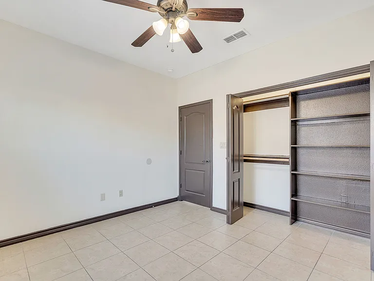 A room in Merida Vista Apartments, Laredo, Texas, showcasing a ceiling fan and closet doors