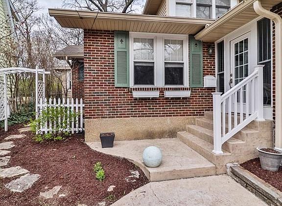 The side yard features a white vinyl arbor and fence and stone pathway