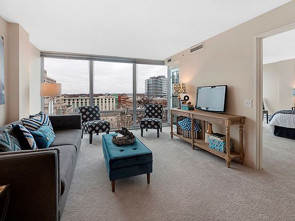 Large living room easily fits a sectional and features floor to ceiling windows with tons of sunligh