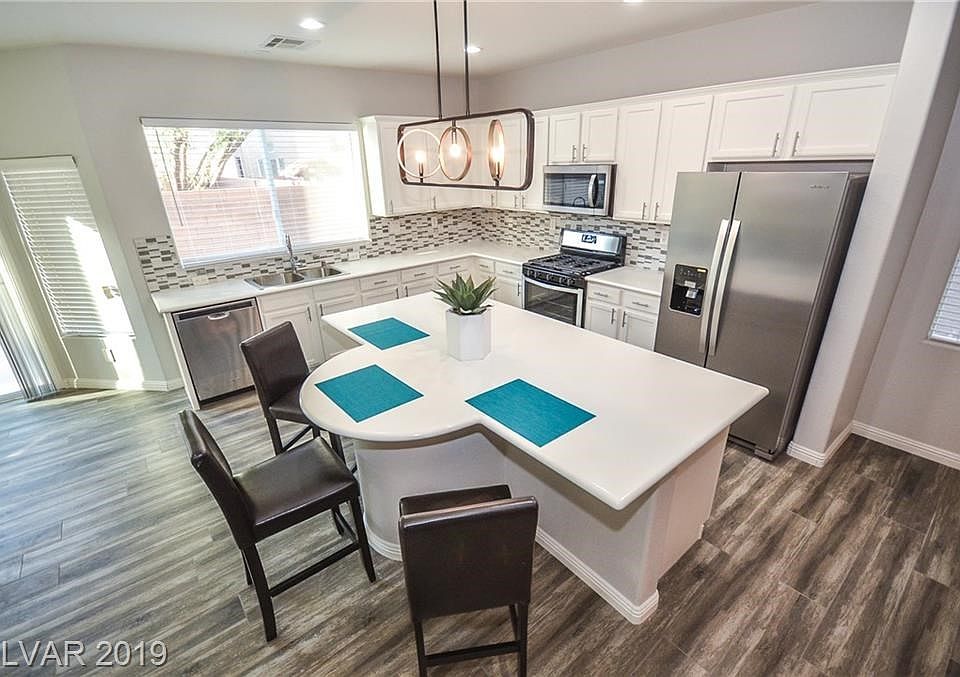 Beautiful white countertops in kitchen & island/breakfast bar highlighted by stylish backsplash!