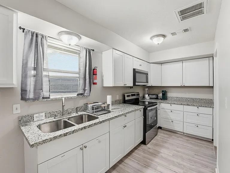 Updated kitchen with granite-look counters, ample white cabinetry, double-basin sink, and full appliance suite.