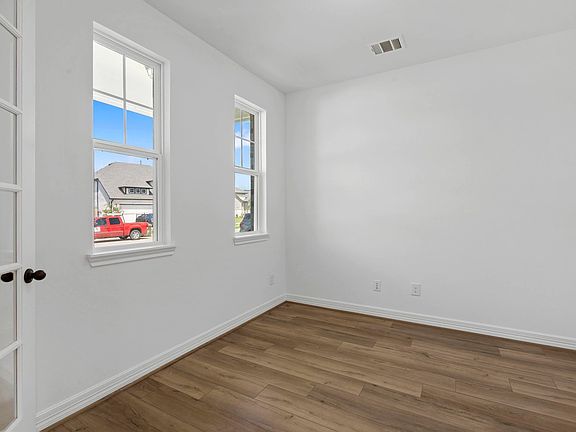 The home office features French doors, beautiful floors, large windows that give a fresh feel, this