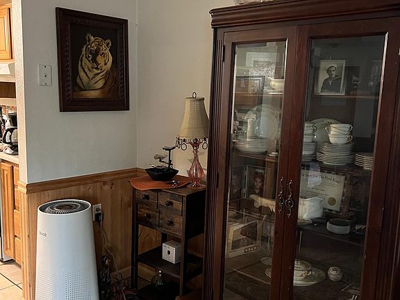 A beautiful corner area china cabinet, an end table, along with an air purifier.