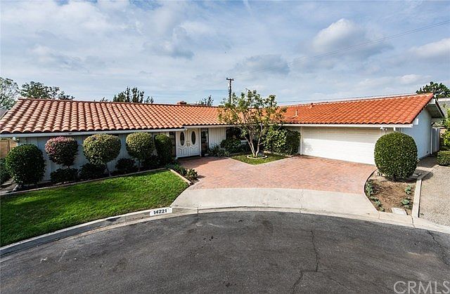 Spanish-tile roof and driveway is of concrete pavers.