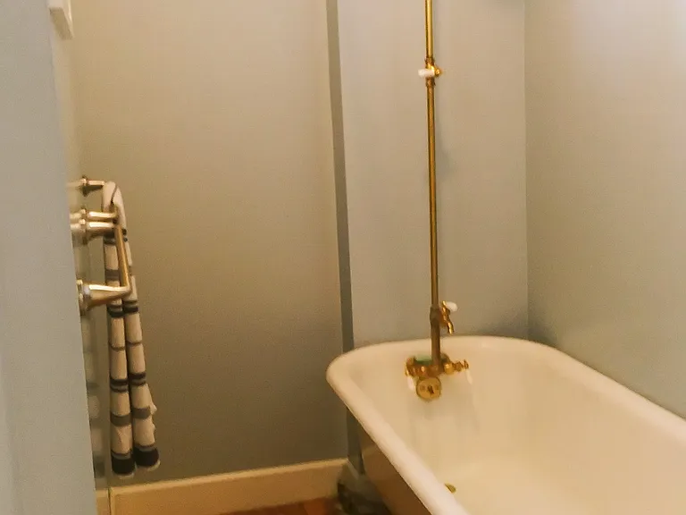 Clawfoot tub in bathroom. Shower curtain is provided.