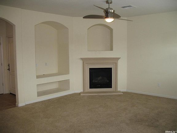 A media niche and gas fireplace are found in the family room.  Look at the interesting fan...