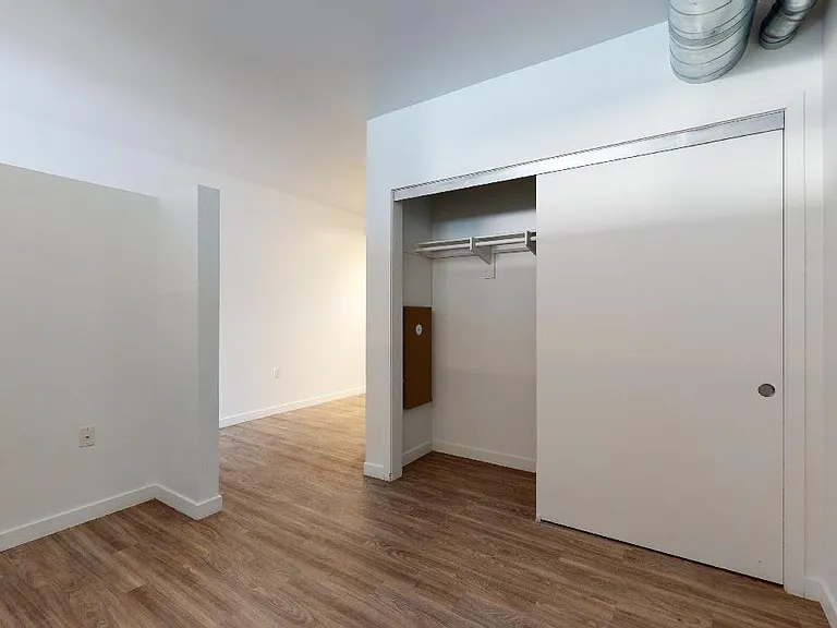 Spacious apartment bedroom with wood-style flooring.