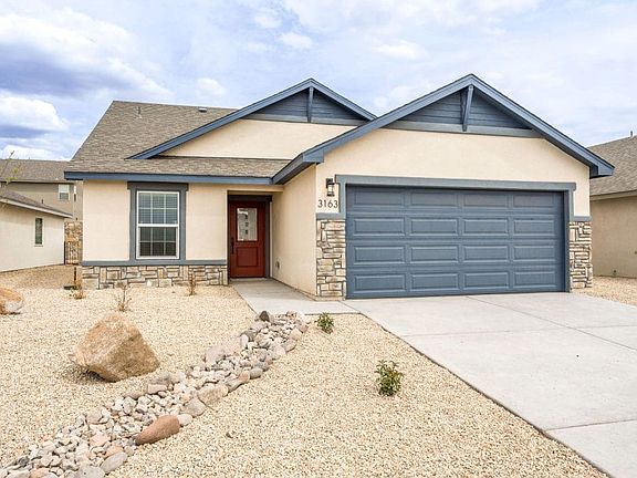 Single-story house with light beige walls, blue trim, stone accents, and a blue double garage. A red