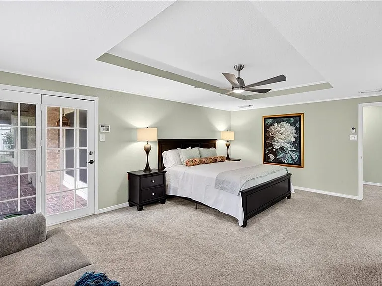 Huge Primary bedroom with seating area and doors out to the covered patio and fenced in back yard.