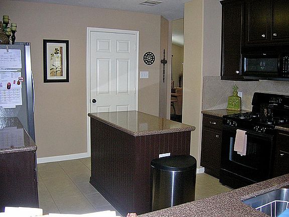 This is the center of daily living in this kitchen with island, granite/quartz counters and contemporary stained cabinets, sleek black appliances.