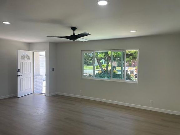 Bright living room area that flows into the kitchen and has a modern ceiling fan