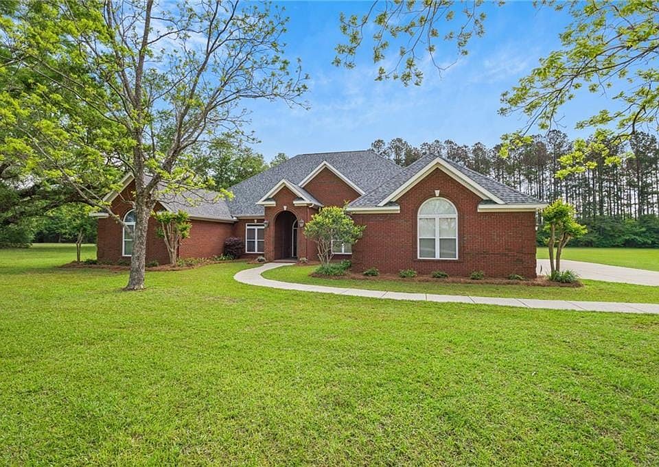 Two story home with brick siding, a shingled roof, and a front yard