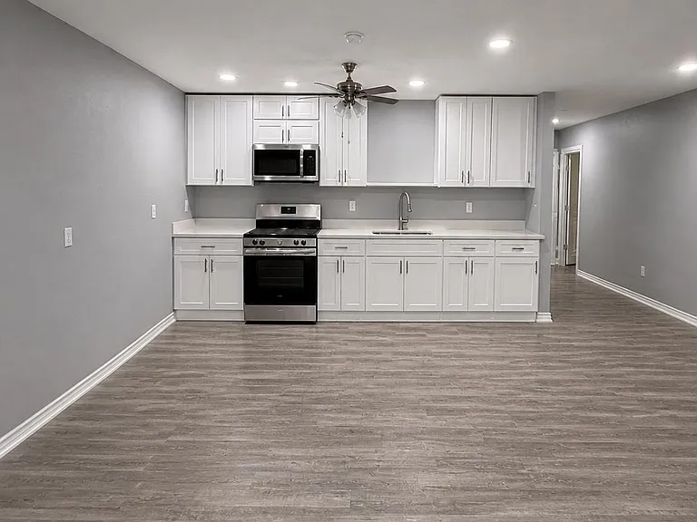 Open kitchen wall with ample white cabinetry, long counters, and stainless range and microwave for everyday cooking.