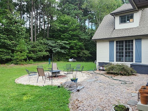 The left side of the home features a charming gravel patio with a cozy fire pit_perfect for evening gatherings, relaxing under the stars, and enjoying the outdoors.