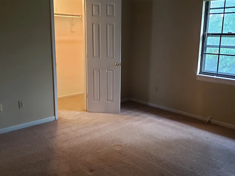 Bigger bedroom showing door to lighted walk in closet.