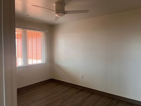 Naturally lit bedroom with modern flooring and a sleek ceiling fan.