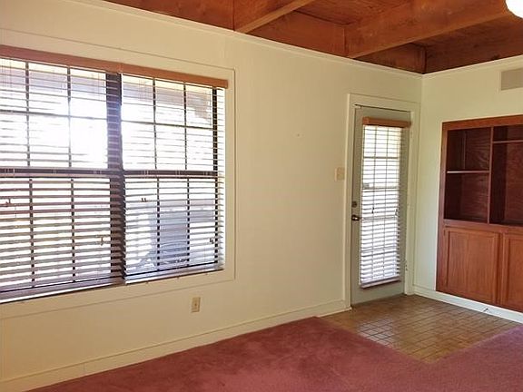 The living room features a built in bookshelf with extra storage and exposed beam ceilings.