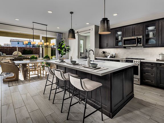 A modern and stylish kitchen with dark cabinets, a large island with bar stools, and a dining area v