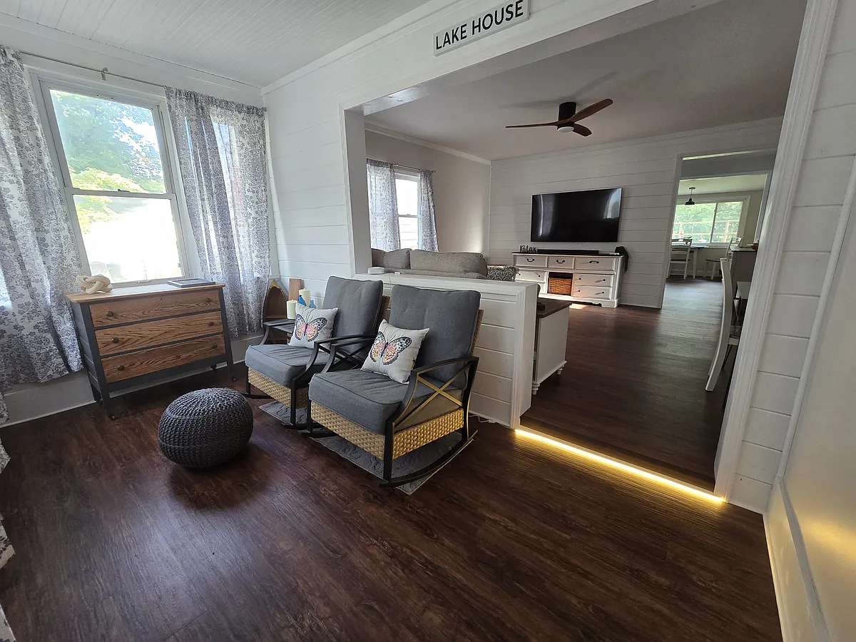 Enclosed front porch w/ rocking chairs. View is looking into the living room then kithen, then dining room to backyard. - Plum Ave