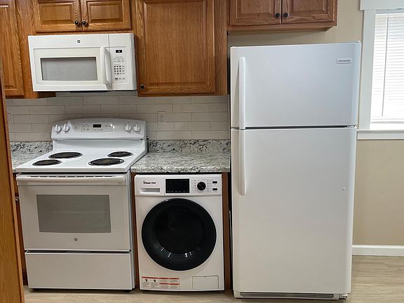 Kitchen has electric stove/oven with overhead microwave and combo washer/dryer and refrigerator/freezer