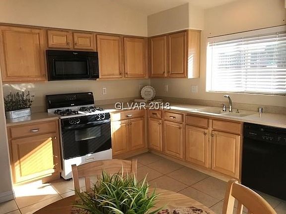 KITCHEN WITH TILE FLOOR AND CORIAN COUNTERTOPS.