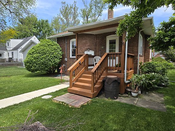 This is the rear view of the home, noting the covered rear deck. There are separate upper and lower entry doors. Sidewalk leads directly to garage. Fenced-in back yard.