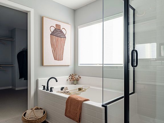 A modern bathroom with a glass shower enclosure, a tiled vanity, and a framed artwork depicting a cu