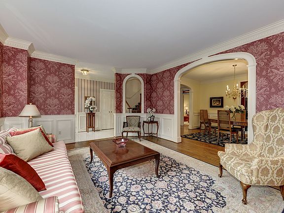 Formal living room featuring 9-foot ceilings, wainscoting, dentil molding, and an arched entry to the dining room
