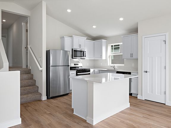 The kitchen has stainless steel appliances and plank flooring.
